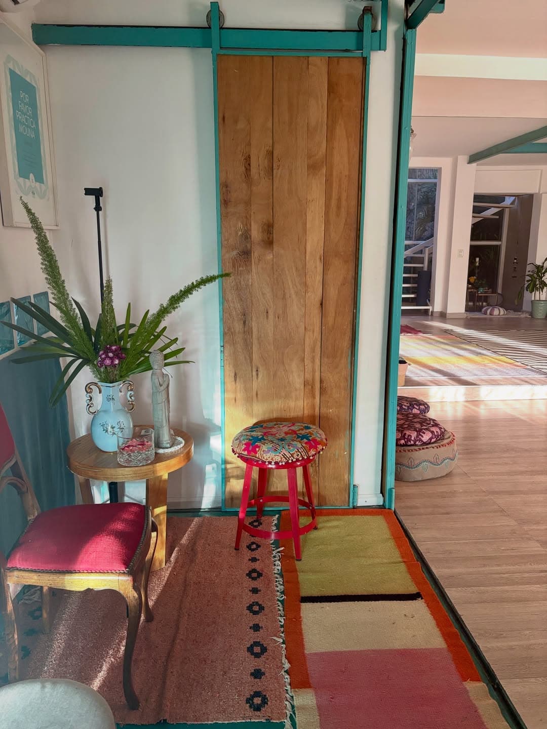 Entrada de is con puerta corrediza de madera, banqueta bordada y alfombras de colores